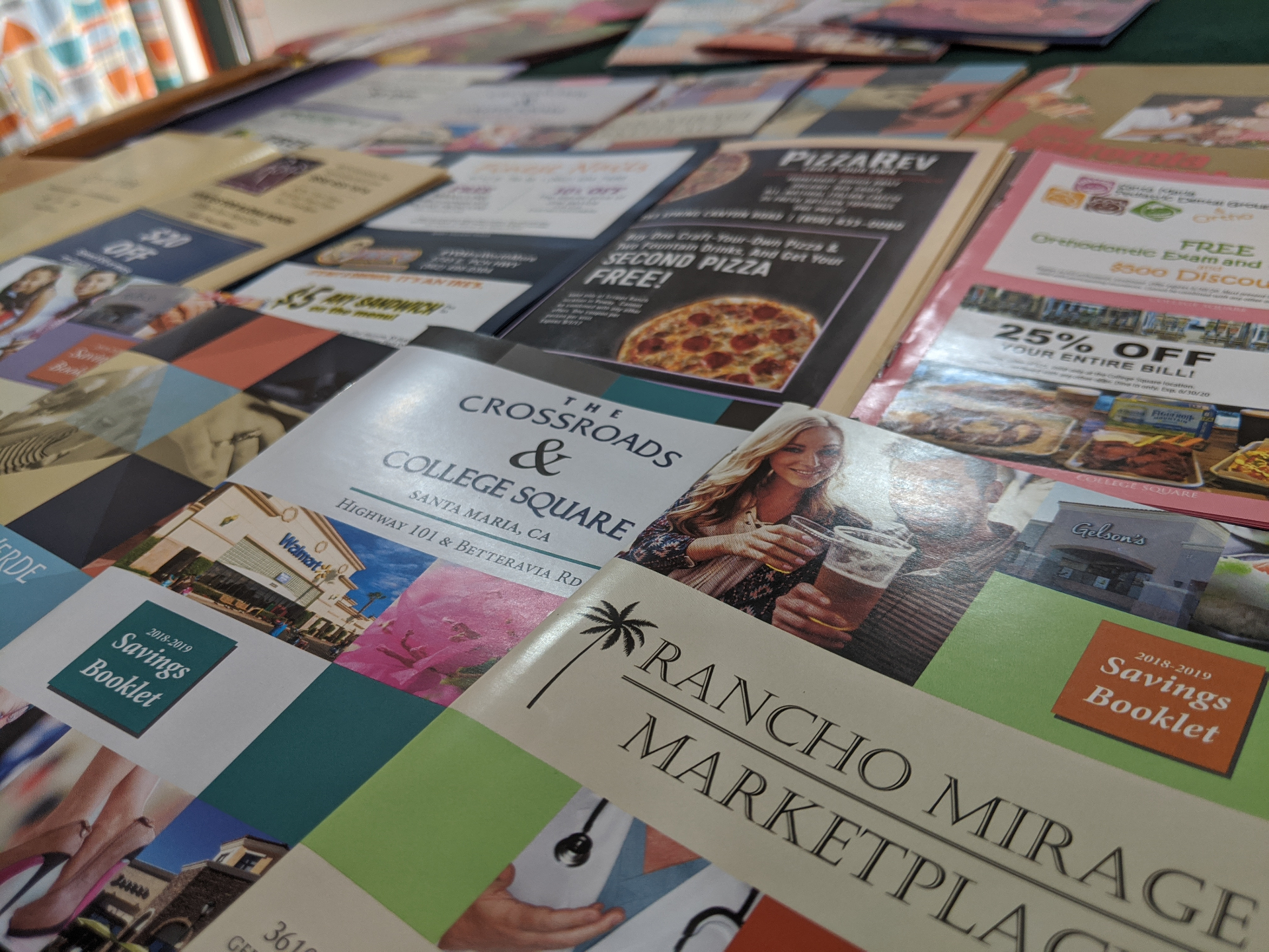 Co-op direct mail booklets and retail promotion pieces spread across a table